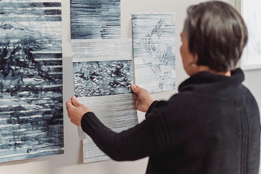 woman hanging artworks up on a wall