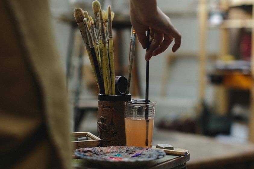 hand holding a paintbrush in an artist's studio